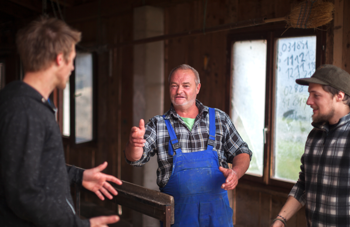Farming Father Talking To His Sons in Agricultural Building - Stock Photo